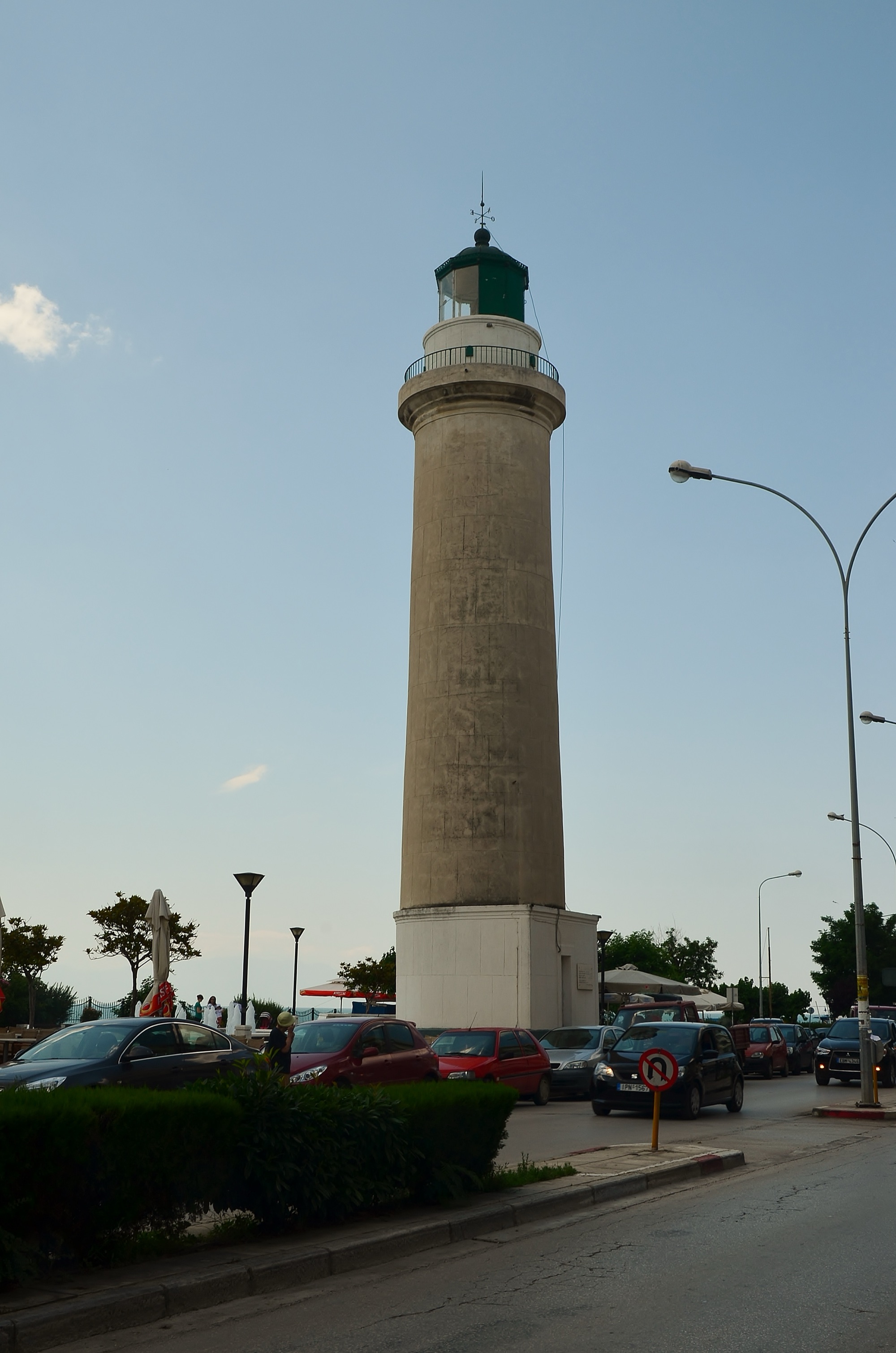 The Alexandroupolis lighthouse at golden hour with cars and people passing by